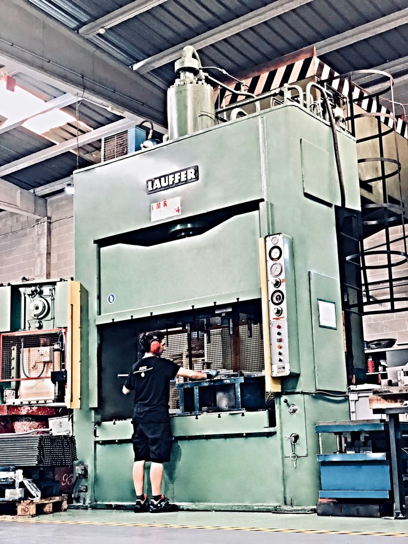 Maquina de estamapciones con estampador trabajando una pieza metalica