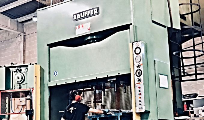 Maquina de estamapciones con estampador trabajando una pieza metalica